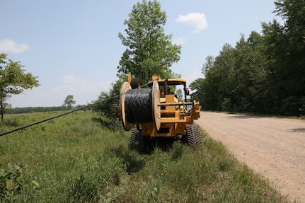 Airmen from five different Engineering Installation Squadrons, including the 205th EIS from Oklahoma, 272nd EIS from Houston, 130th from Utah, and the 223rd EIS from New York, work together to install fiber optics cables across Minnesota's Camp Ripley Training Center's training areas on July 15, 2021.