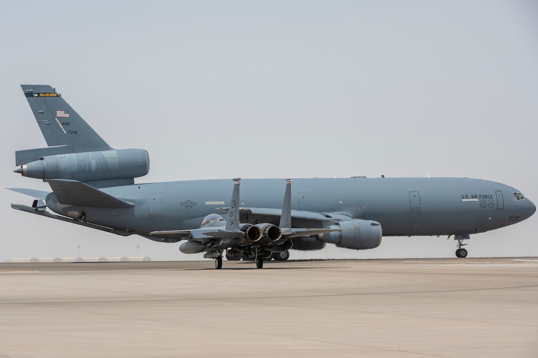 A KC-10 Extender from the 908th Expeditionary Air Refueling Squadron and an F-15E Strike Eagle assigned to the 494th Expeditionary Fighter Squadron prepare for takeoff July 5, 2021 from Al Dhafra Air Base, United Arab Emirates. With assistance from the KC-10 Extender aircraft, the F-15s and their associated equipment and crew are able to return to their home station in one consolidated mission, maximizing use of time and resources. (U.S. Air Force photo by Master Sgt. Wolfram M. Stumpf)