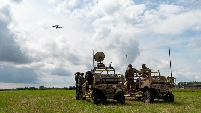 A distant view of Airmen standing next to tents and antenna.