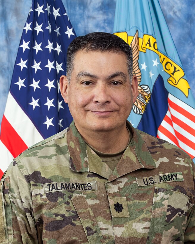 Man in military uniform with 2 flags behind him