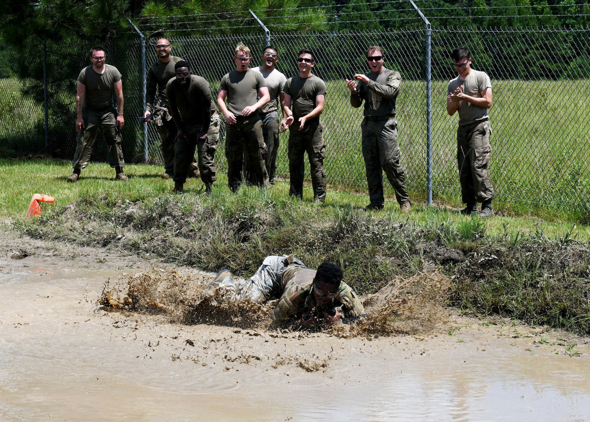 Military member low crawling in muddy water