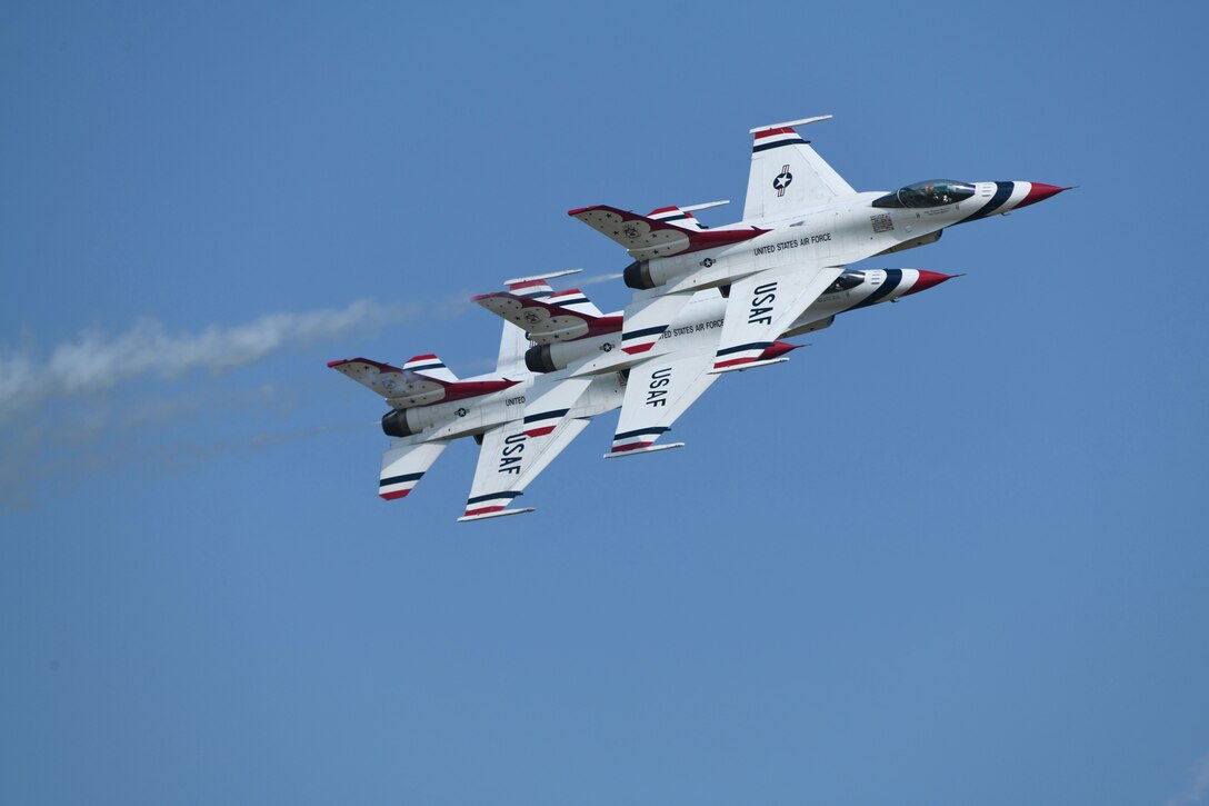 Air Force jets fly in a tight line in blue sky.