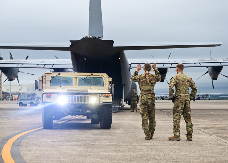 Two Airmen assigned to the 41st Airlift Squadron load a High Mobility Multipurpose Wheeled Vehicle into a C-130J Super Hercules
