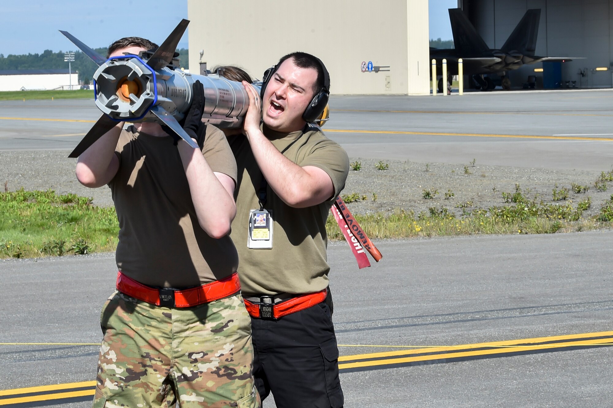 A weapons load crew from the 90th Aircraft Maintenance Unit carry an AIM-9X missile during a Weapons Load Crew of the Quarter competition at Joint Base Elmendorf-Richardson, Alaska, July 1, 2021. Airmen from the 525th and 90th Aircraft Maintenance Units competed for the title of the 3rd Maintenance Group Load Crew of the Quarter.