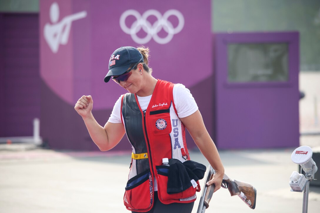 A soldier clenches her fist in victory while holding a rifle in her other hand.