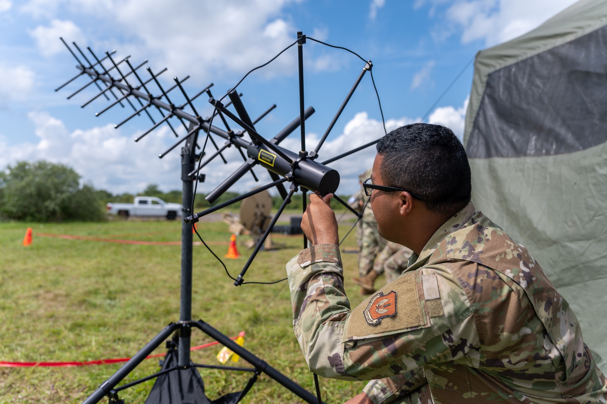 An Airman kneeling behind an antenna.