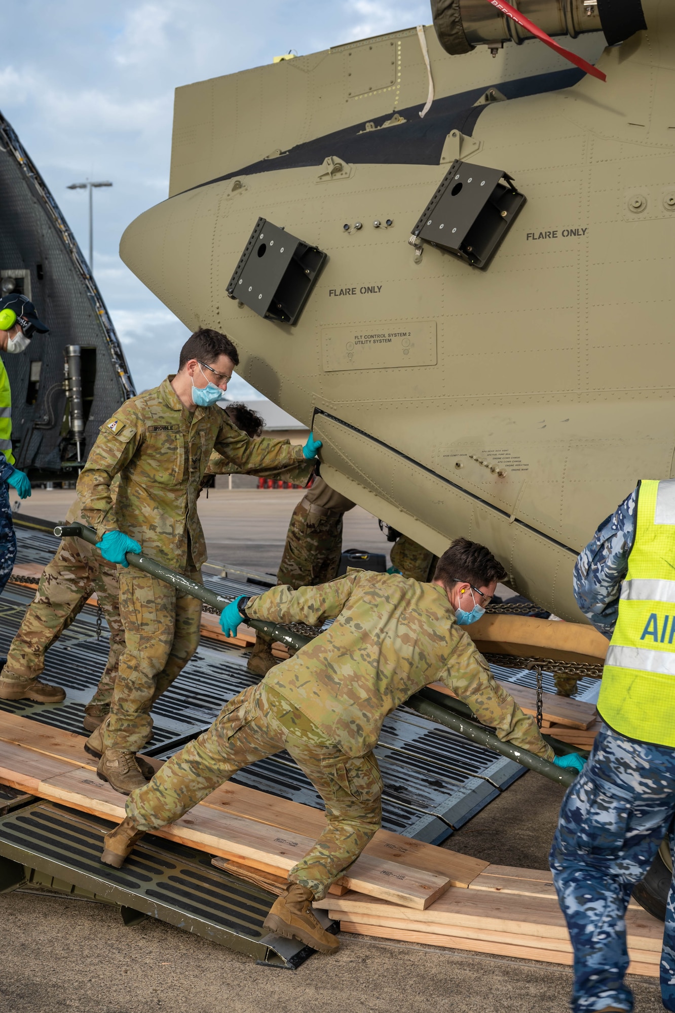 Members of the Royal Australian Army unload a CH-47H Chinook helicopter from a Dover Air Force Base C-5M Super Galaxy at Royal Australian Air Force Base Townsville, Australia, July 7, 2021. The C-5 transported two CH-47F Chinook helicopters to RAAF Base Townsville as a part of the Department of Defense’s Foreign Military Sales program. The U.S. and Australia maintain a robust relationship underpinned by shared democratic values, common interests and cultural bonds. The strong alliance is an anchor for peace and stability in the Indo-Pacific region and around the world. (U.S. Air Force photo by Senior Airman Faith Schaefer)