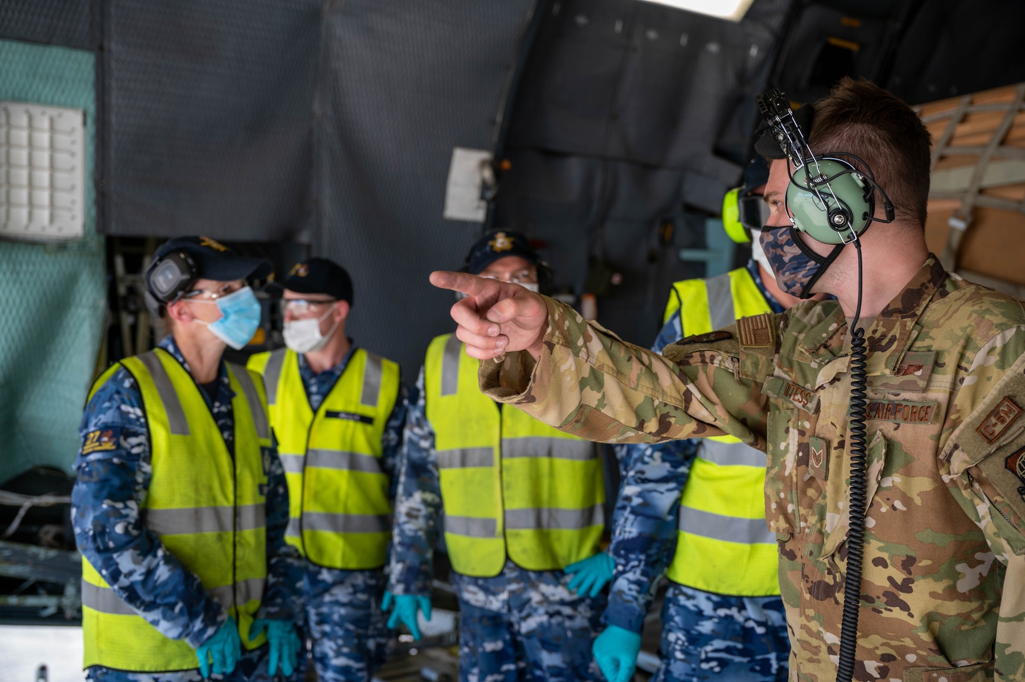 U.S. Air Force Staff Sgt. John Dittess, 9th Airlift Squadron loadmaster, discusses unloading procedures to Royal Australian Air Force airmen aboard a Dover Air Force Base C-5M Super Galaxy, at RAAF Base Townsville, Australia, July 7, 2021. The C-5 transported two CH-47F Chinook helicopters to RAAF Base Townsville as a part of the Department of Defense’s Foreign Military Sales program. The U.S. and Australia maintain a robust relationship underpinned by shared democratic values, common interests and cultural bonds. The strong alliance is an anchor for peace and stability in the Indo-Pacific region and around the world. (U.S. Air Force photo by Senior Airman Faith Schaefer)