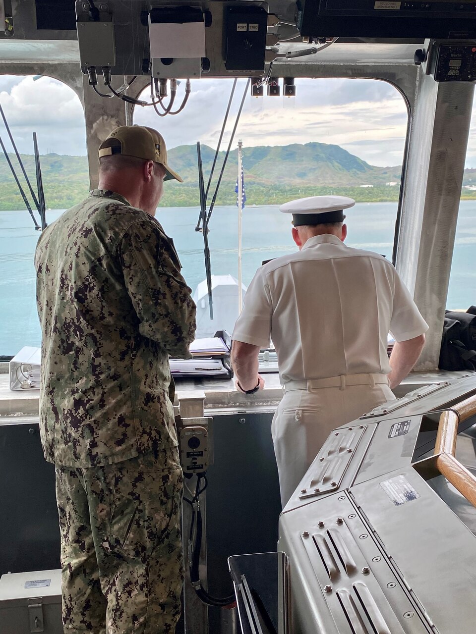 CNO Gilday and the Commanding Officer of USS Charleston look out the windows of the bridge of the ship.