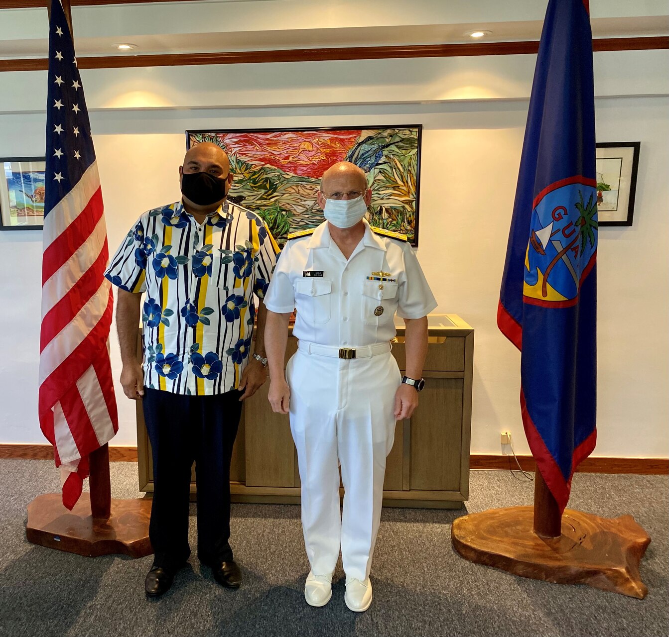 CNO Gilday and Acting Guam Governor pose for a photo in front of Guam and US flags.