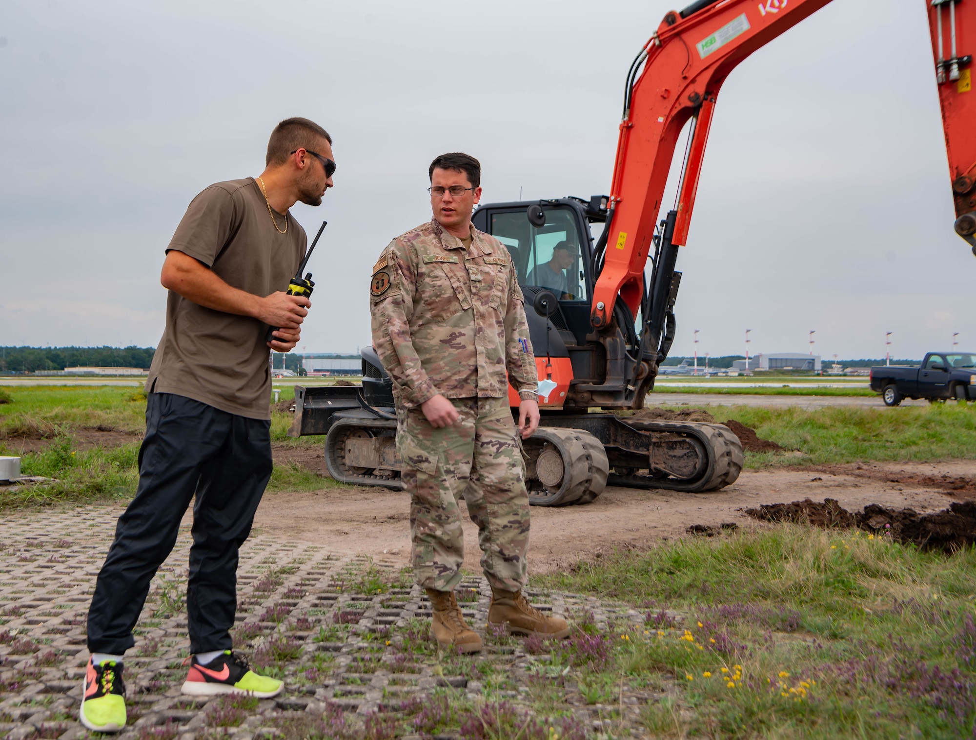 U.S. Air Force Senior Airman James Jones, a controlled movement area escort and project manager assigned to the 86th Civil Engineering Squadron,  talks to an escort augmentee at a construction site at Ramstein Air Base, Germany, July 27, 2021. Escort workers make sure that the contractors do not cross over restricted area lines and stay away from certain areas when planes are landing for security and safety of everyone on the airfield. 
(U.S. Air Force photo by Airman Jared Lovett)