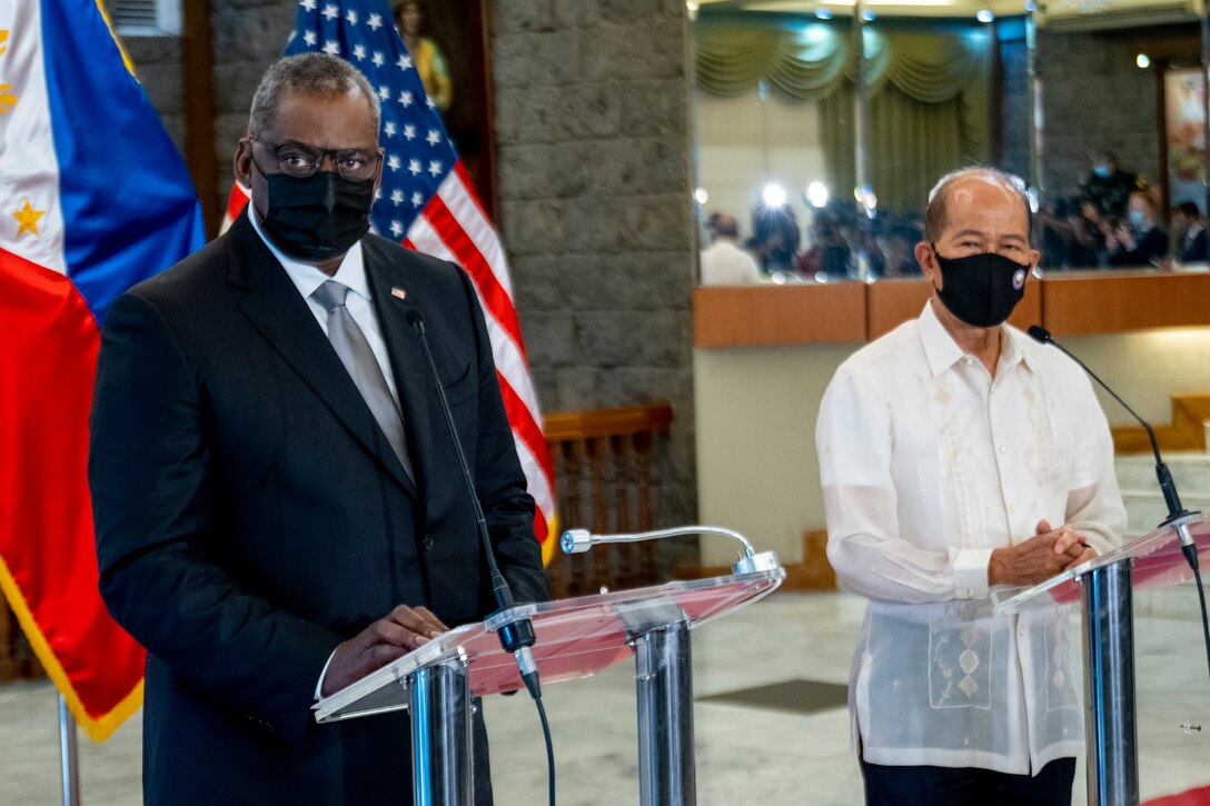 Two men stand next to each wearing masks.