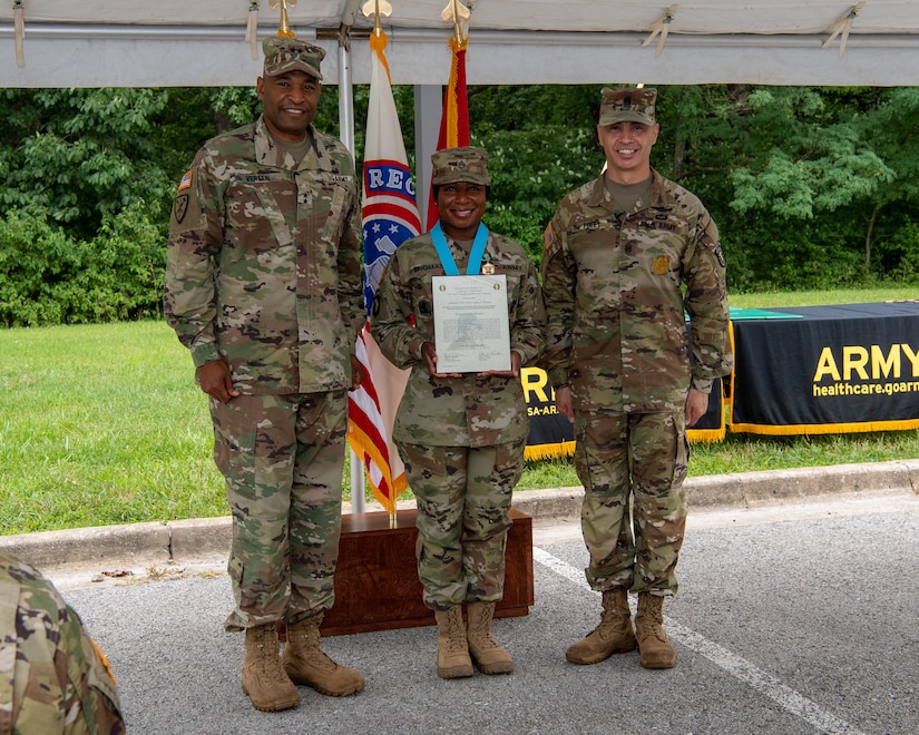 three soldiers posing for a photo in front of flags.