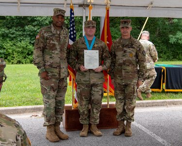 three soldiers posing for a photo in front of flags.