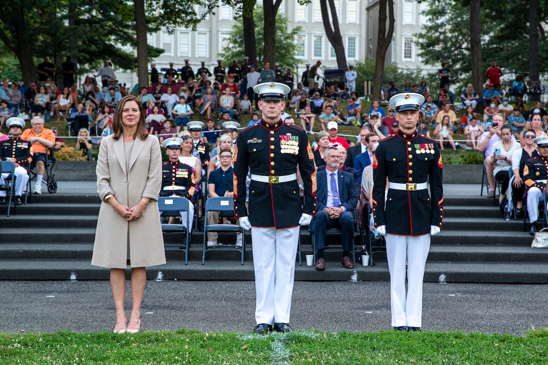 From Left, Ms. Melissa Cohen, Director, Department of the Navy Sexual Assault Prevention and Response Office, Sgt. Maj. Troy E. Black, Sergeant Major of the Marine Corps, and Cpl. Coleton Bihn, administration specialist, Marine Barracks Washington, stand at the position of attention during the Non-Commissioned Officer Tuesday Sunset Parade at the Marine Corps War Memorial, Arlington, Va., July 27, 2021.