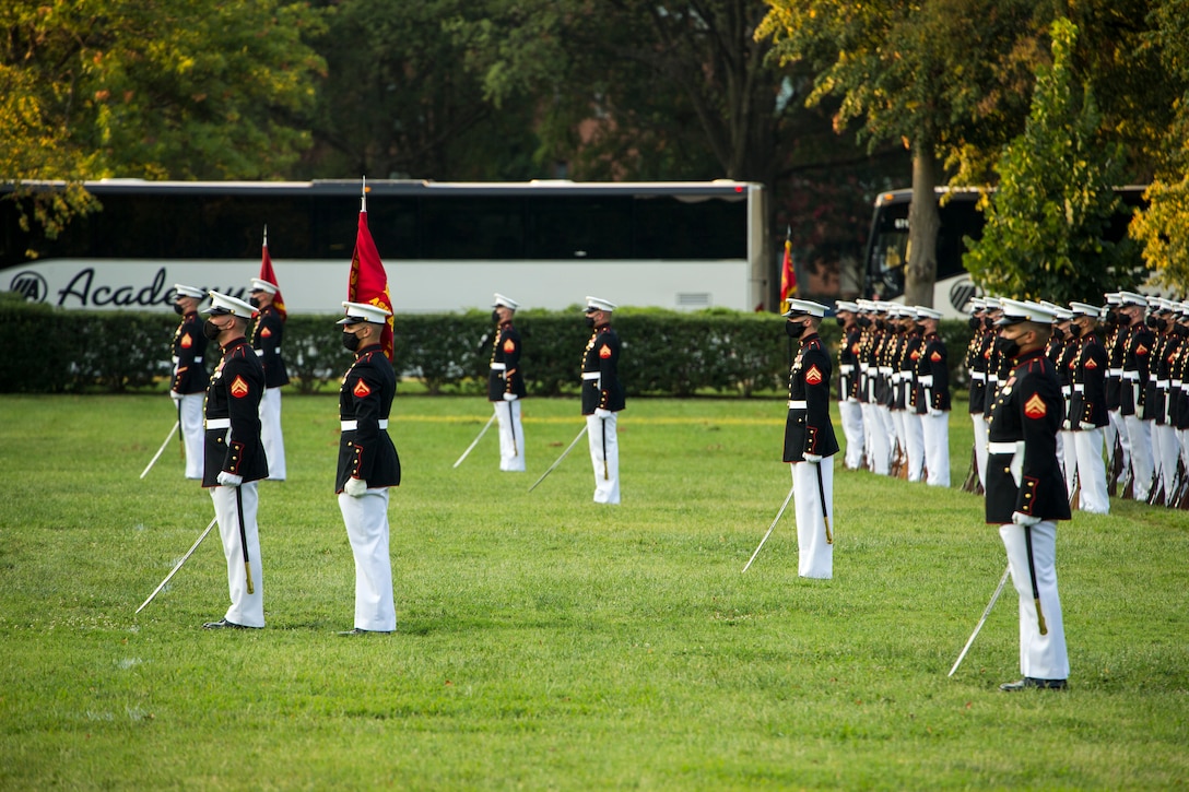 Marines with Marine Barracks Washington stand at the position of attention during the Non-Commissioned Officer Tuesday Sunset Parade at the Marine Corps War Memorial, Arlington, Va., July 27, 2021. The hosting official for the evening was Sgt. Maj. Troy E. Black, Sergeant Major of the Marine Corps, and the guest of honor was Ms. Melissa Cohen, Director, Department of the Navy Sexual Assault Prevention and Response Office. (U.S. Marine Corps photo by Lance Cpl. Allen Sanders)