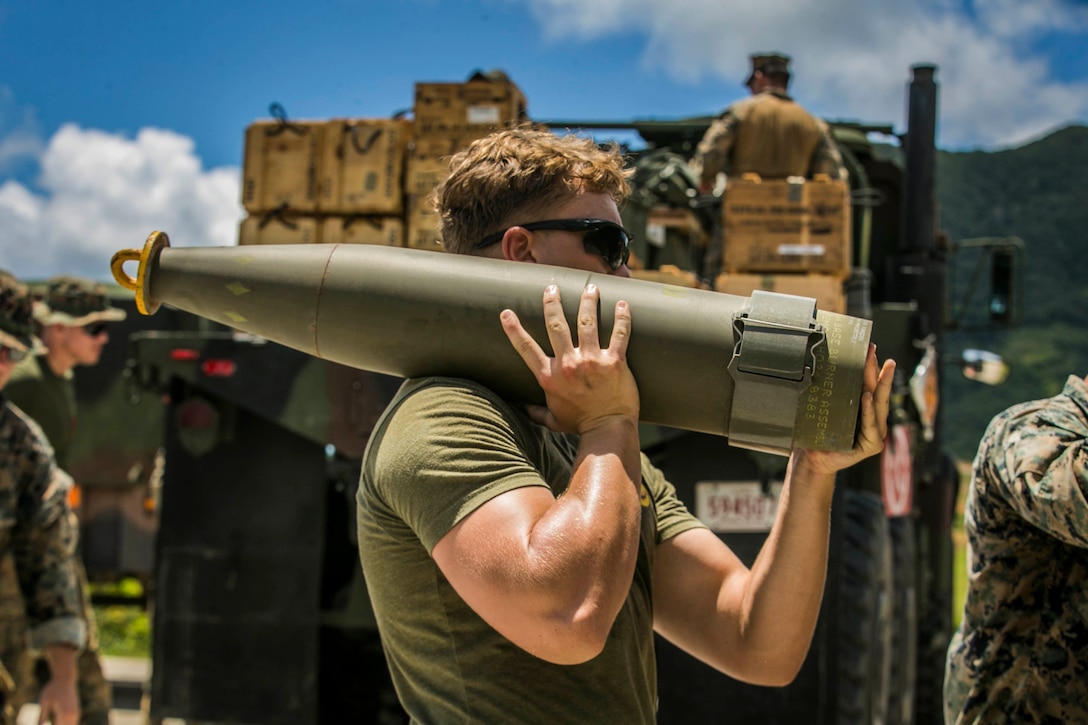 A Marine carries an artillery round.