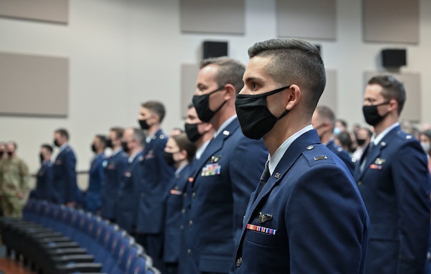 Graduates from the Specialized Undergraduate Pilot Training class 21-13, stand at attention during the National Anthem, July 30, 2021, on Columbus Air Force Base, Miss. A total of 30 aviators earned the title of U.S. Air Force Pilot, after completing a 52-week SUPT course. (U.S. Air Force photo by Airman 1st Class Jessica Haynie)