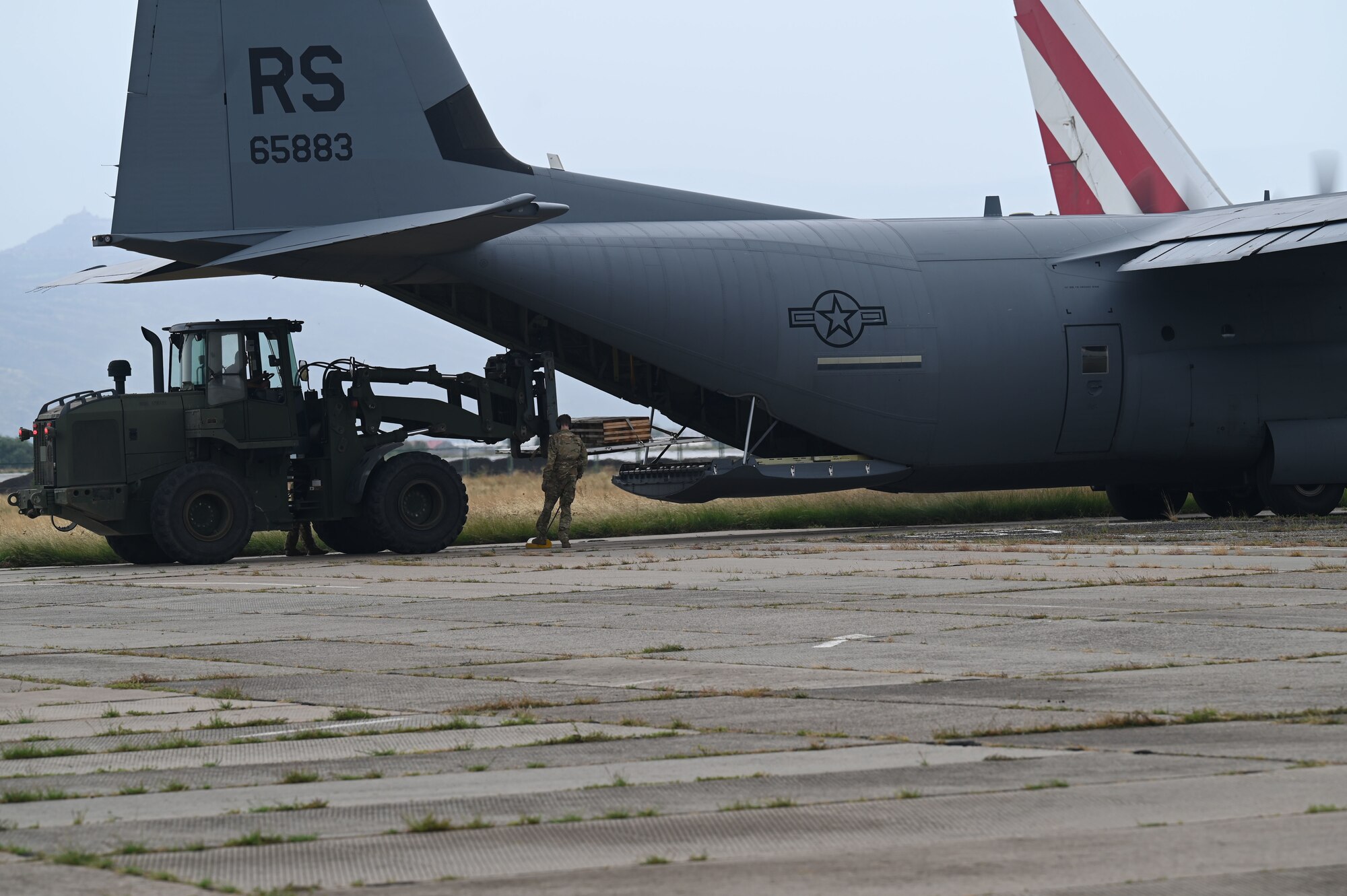 A U.S. Air Force loadmaster assigned to the 37th Airlift Squadron supervises a Georgian military member placing cargo in a U.S. Air Force C-130J Super Hercules aircraft during exercise Agile Spirit 21