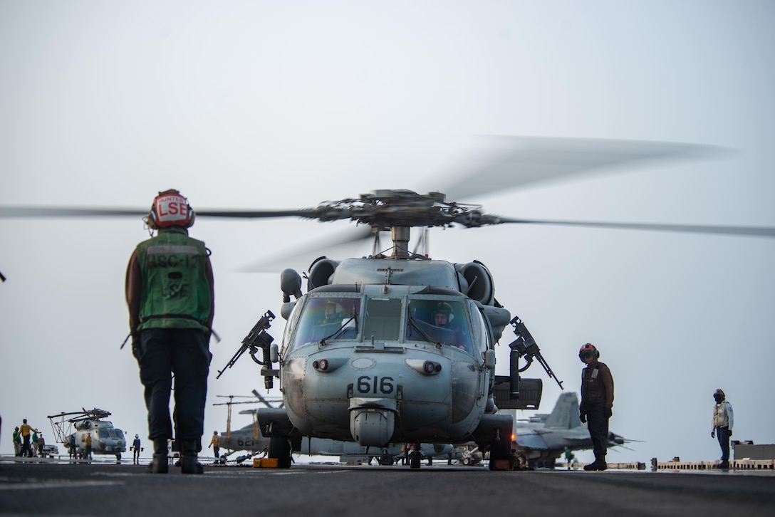 210730-N-WS494-1288 ARABIAN SEA (July 30, 2021) – Sailors prepare an MH-60S Sea Hawk helicopter, attached to the “Golden Falcons” of Helicopter Sea Combat Squadron (HSC) 12, to launch on the flight deck of aircraft carrier USS Ronald Reagan (CVN 76) in response to a call for assistance from a vessel in distress in the Arabian Sea, July 30. Ronald Reagan is deployed to the U.S. 5th Fleet area of operations in support of naval operations to ensure maritime stability and security in the Central Region, connecting the Mediterranean and Pacific through the western Indian Ocean and three strategic choke points. (U.S. Navy photo by Mass Communication Specialist 2nd Class Quinton A. Lee)