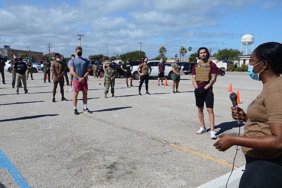 A sailor holds a microphone while talking to other sailors standing around.