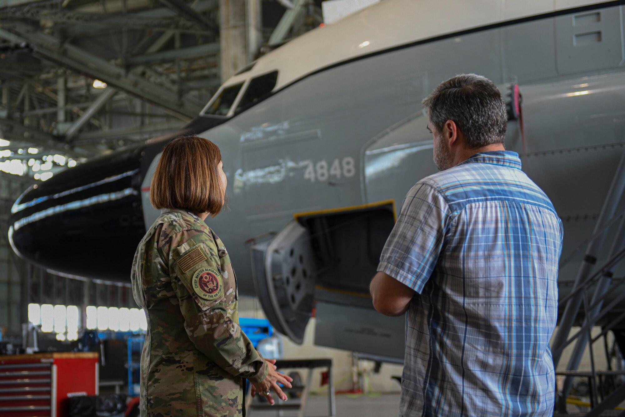 Chief Master Sergeant of the Air Force JoAnne S. Bass looks at a rc-135V/W Rivet Joint aircraft as a man talks to her.