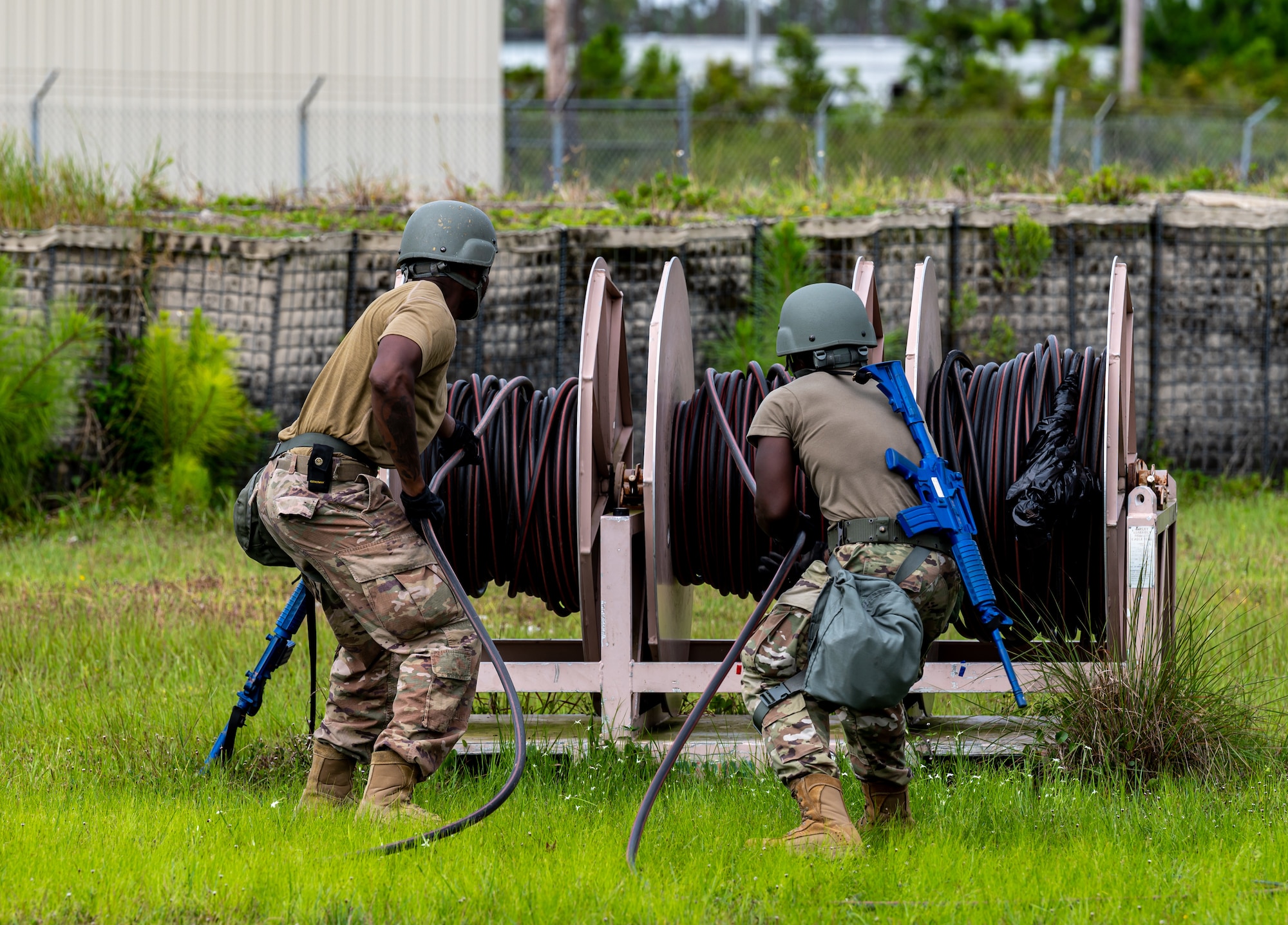 Photo of two Airmen pulling a cable