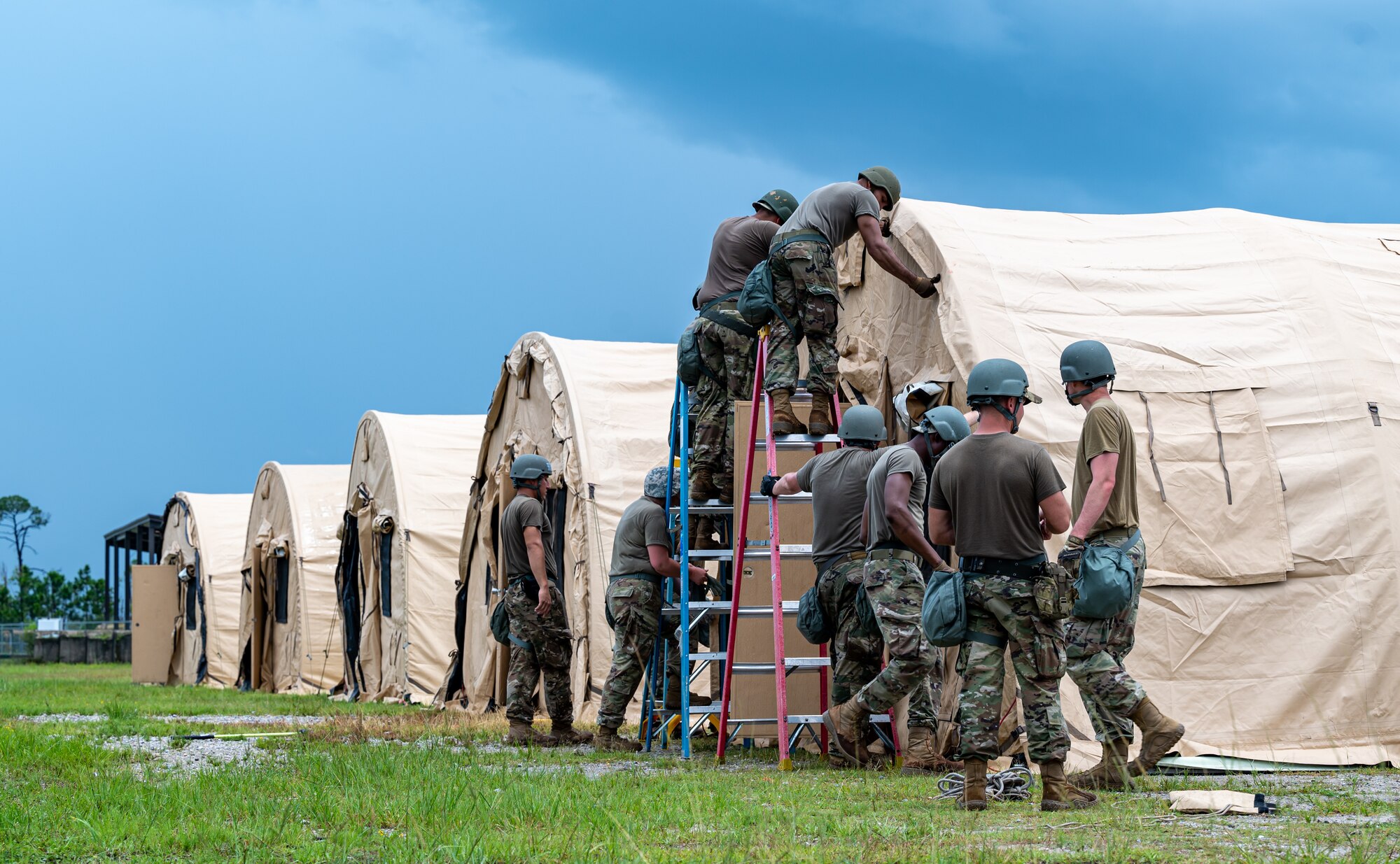 Photo of Airmen pinning a cover on a temporary shelter