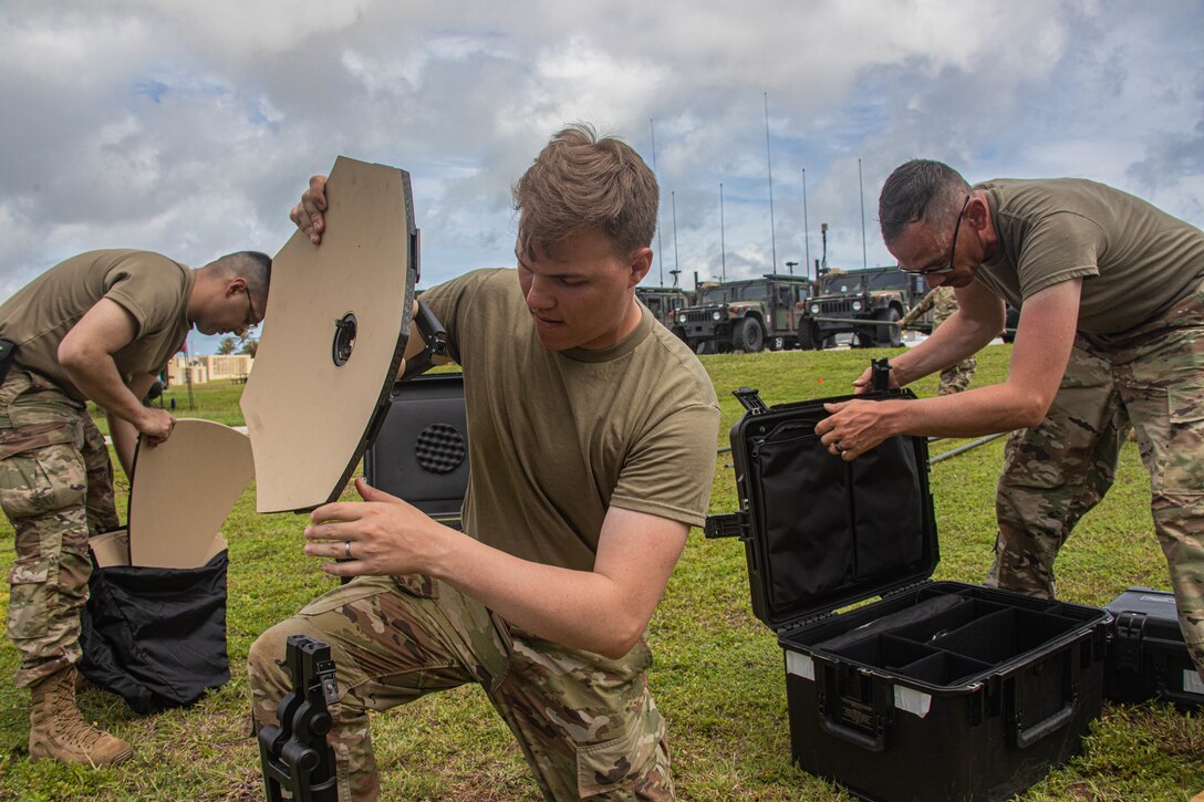 Three young soldiers set up equipment.