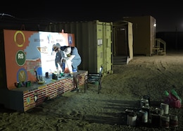 Chief Warrant Officer 2 Paul Viall, information systems technician, assigned to the 310th Sustainment Command (Expeditionary), works at night with the aid of a projector to trace out the design of the unit mural or unit T-wall, Camp Arifjan, Kuwait.  Viall worked countless hours to paint a mural that will represent the hard work and dedication of the Army Reserve’s Indianapolis-based “Brickyard” Soldiers and their time serving within the U.S. Central Command’s area of responsibility.