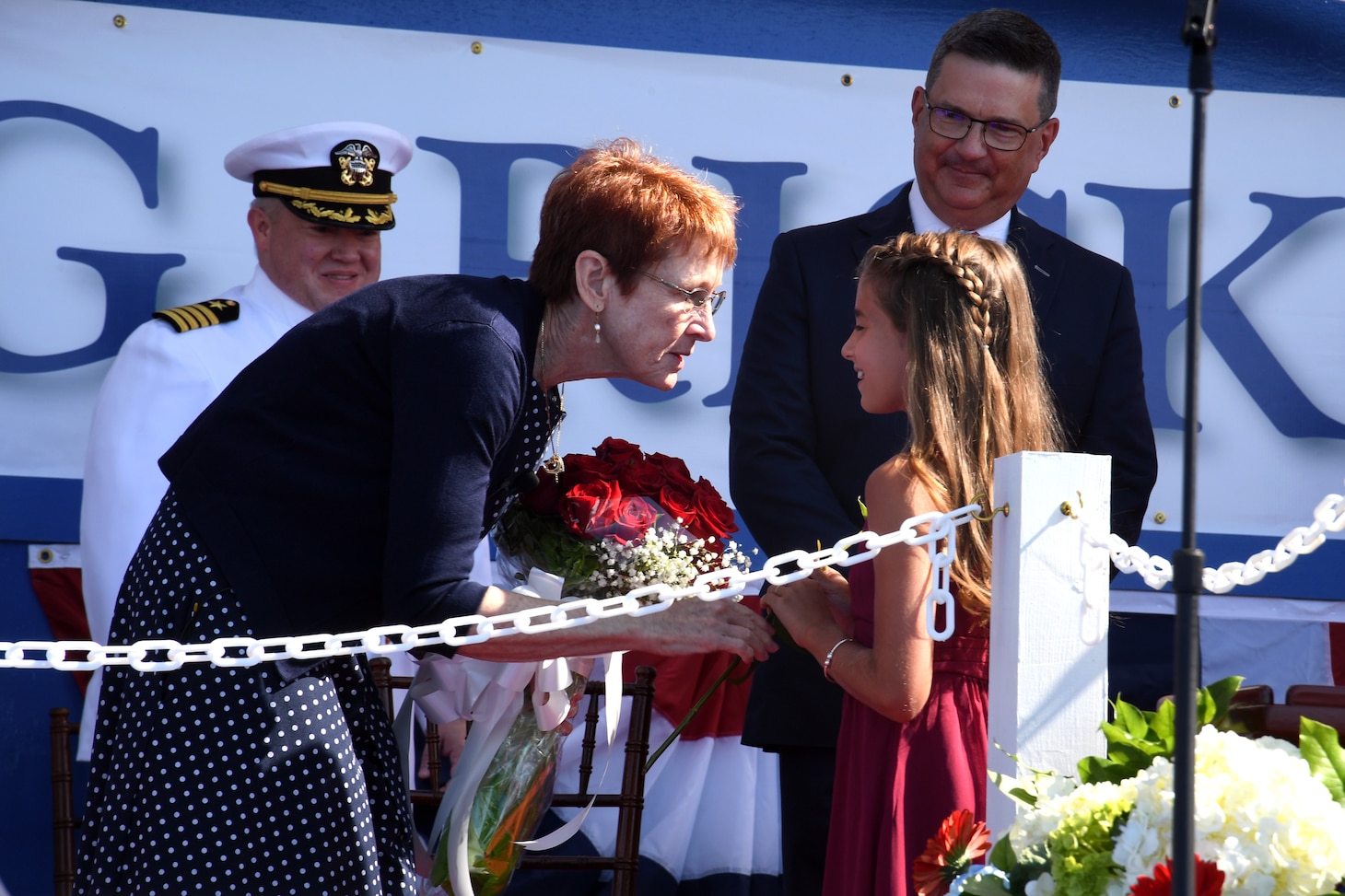 Darleen Greenert, sponsor of the pre-commissioning unit (PCU) Hyman G. Rickover (SSN 795), hands a flower to Mya Rae Marsiglio, a granddaughter of a shipyard employee, during a christening ceremony at General Dynamics Electric Boat shipyard facility in Groton, Conn., July 31, 2021.