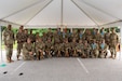 large group of soldiers in army uniform standing in front of flags.