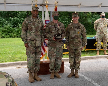 three soldiers in army uniforms standing in front of flags.