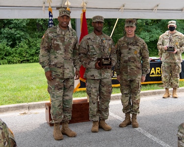 three soldiers in army uniforms standing in front of flags.