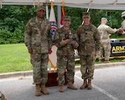 three soldiers in army uniforms standing in front of flags.