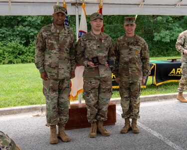 four men and women in army uniforms standing in front of flags.