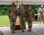 four men and women in army uniforms standing in front of flags.