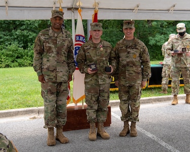 four men and women in army uniforms standing in front of flags.