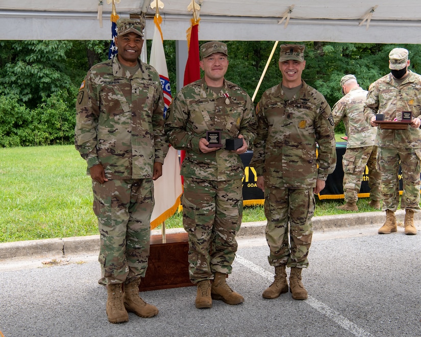 four men and women in army uniforms standing in front of flags.