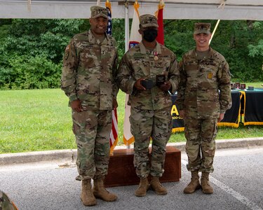 four men and women in army uniforms standing in front of flags.
