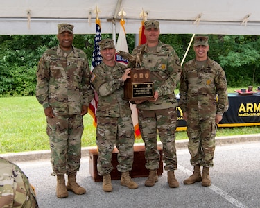 four men and women in army uniforms standing in front of flags.