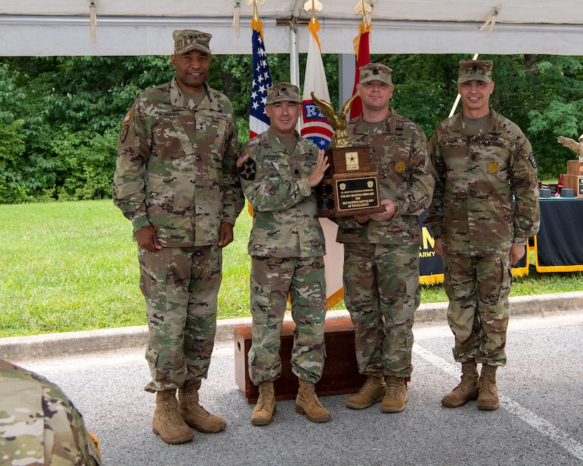 four men and women in army uniforms standing in front of flags.