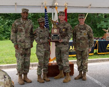 four men and women in army uniforms standing in front of flags.