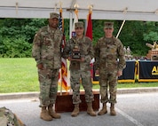 three men in army uniforms standing in front of flags.