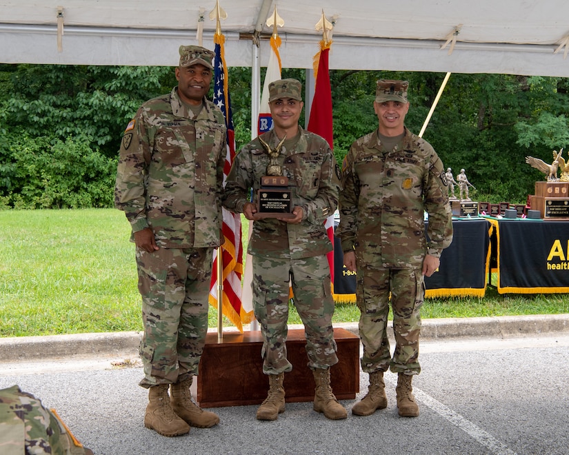 three men in army uniforms standing in front of flags.