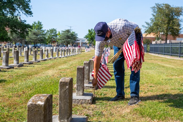 Norfolk Naval Shipyard Veteran Employee Readiness Group founding member Jonathan Echols places flags on the graves of fallen service members during the annual flag placement ceremony at the Captain Ted Conaway Memorial Naval Cemetery in Naval Medical Center Portsmouth (NMCP) May 27.