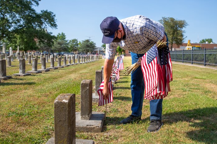 Norfolk Naval Shipyard Veteran Employee Readiness Group founding member Jonathan Echols places flags on the graves of fallen service members during the annual flag placement ceremony at the Captain Ted Conaway Memorial Naval Cemetery in Naval Medical Center Portsmouth (NMCP) May 27.