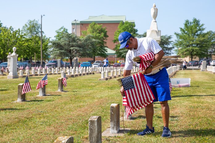 Naval Support Activity Hampton Roads Portsmouth Site Director Kenneth Pugh places flags on the graves of fallen service members during the annual flag placement ceremony at the Captain Ted Conaway Memorial Naval Cemetery in Naval Medical Center Portsmouth (NMCP) May 27.