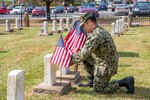 A Sailor stationed at Naval Support Activity Hampton Roads Portsmouth places flags on the graves of fallen service members during the annual flag placement ceremony at the Captain Ted Conaway Memorial Naval Cemetery in Naval Medical Center Portsmouth (NMCP) May 27.