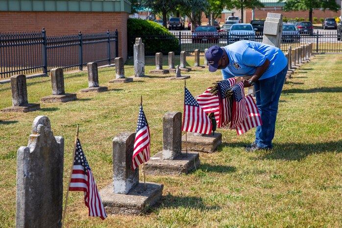 Ricky Burroughs, a member of the Norfolk Naval Shipyard Veteran Employee Readiness Group, places flags on the graves of fallen service members during the annual flag placement ceremony at the Captain Ted Conaway Memorial Naval Cemetery in Naval Medical Center Portsmouth (NMCP) May 27.